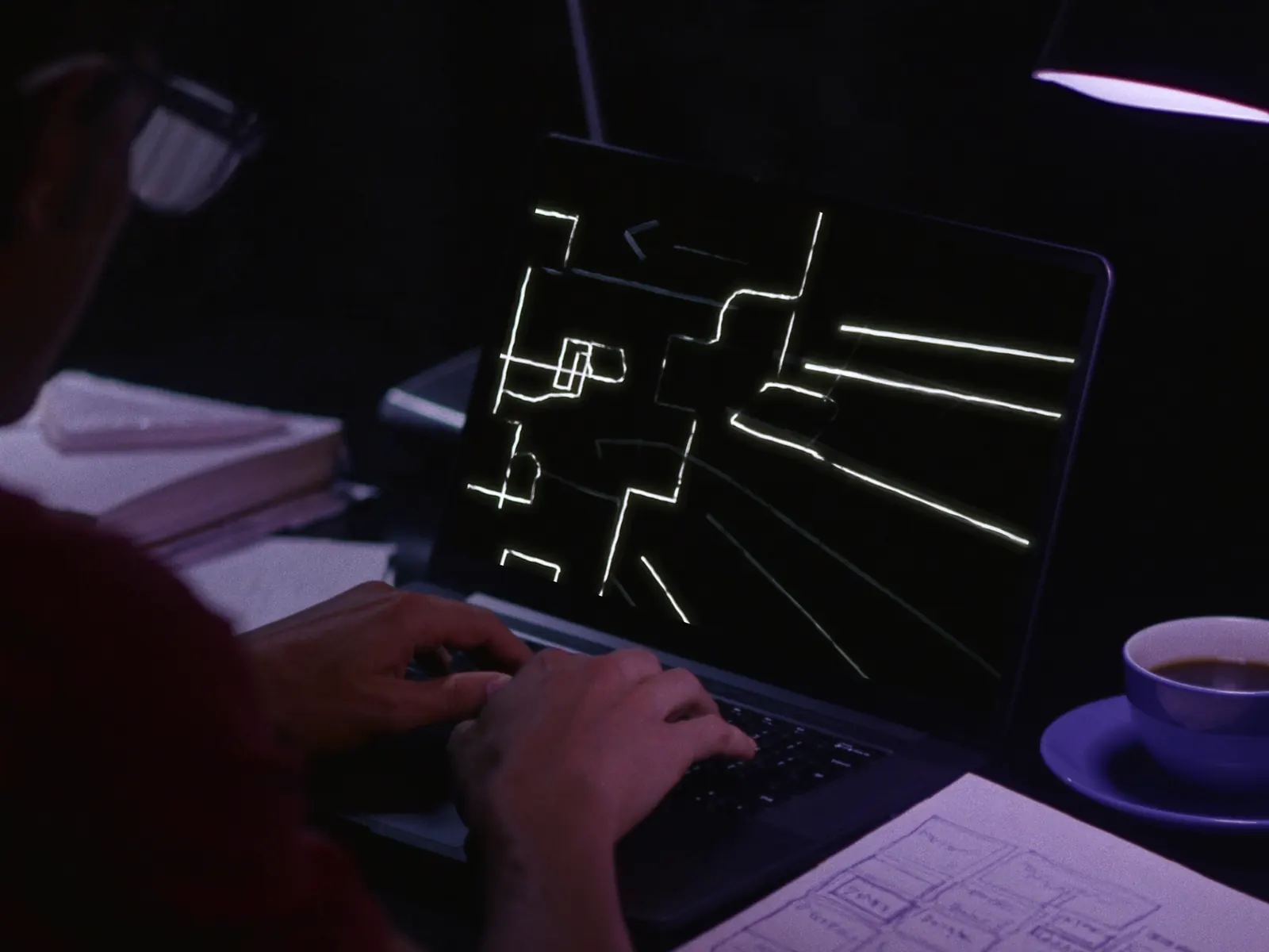 Manos sobre un portátil con un diagrama en pantalla y un cuaderno con bocetos